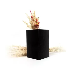 vase funéraire en granit noir contenant un bouquet de fleurs séchées